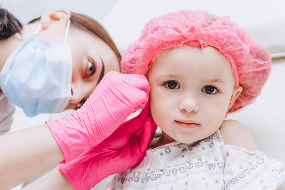 Children's ear piercing: Image by Anna Nass via Shutterstock - Charming little girl having an ear piercing process