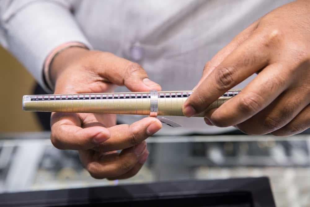 mage by Katiekk via Shutterstock - 2 hands measuring the size of a ring